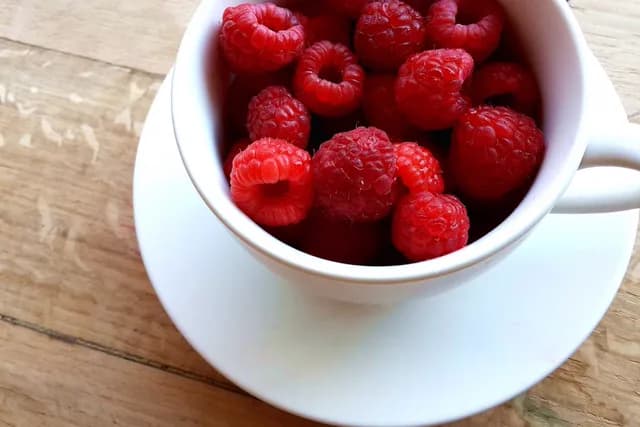 Cup of raspberries on a wooden table, upscaled